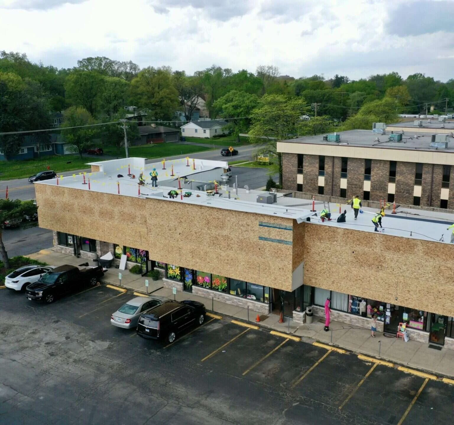 Aerial view of a crew working on the flat roof of a strip-mall commercial building