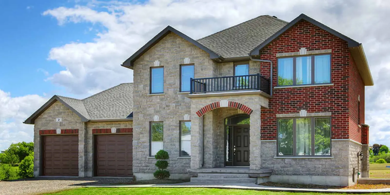 Two-story brick and stone home with large front windows and a second-floor balcony