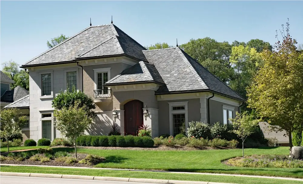 Stone French-style home with a steep gray slate roof